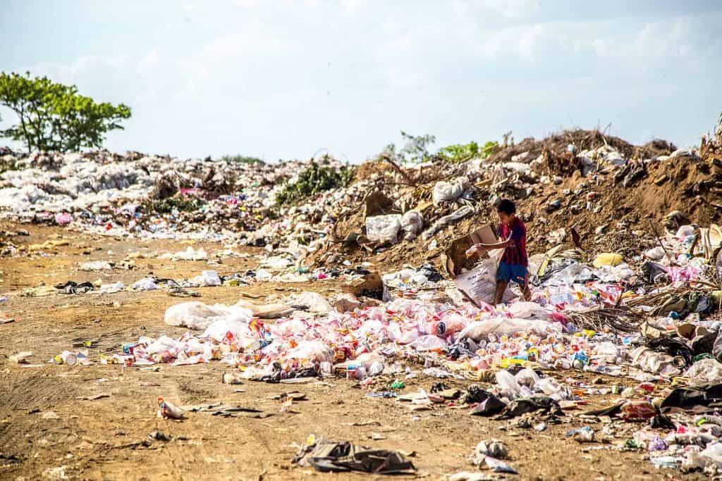 Why do we litter? Child hunting through the expanse of litter strewn across an earthly landscape.